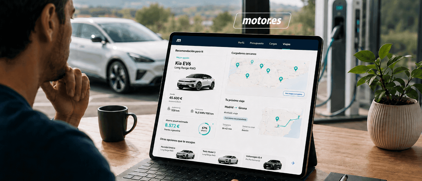 Persona usando un portátil sobre escritorio de madera con la integración QuantumDrive en Motor.es visible — recomendación de Kia EV6, ahorro anual, mapa de cargadores cercanos y próximo viaje Madrid-Girona