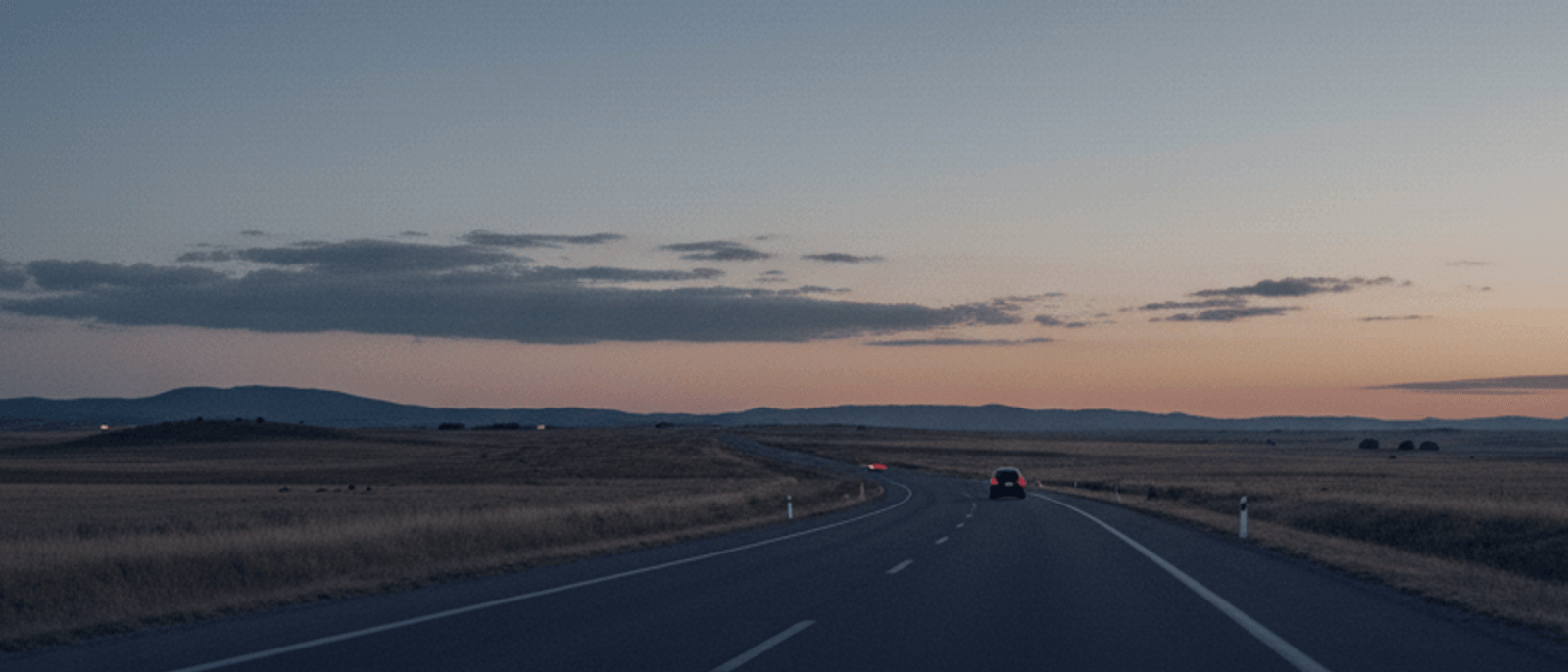 Atardecer en autovía española camino a Valencia con un coche eléctrico circulando hacia el horizonte — montañas, cielo cálido y carretera abierta